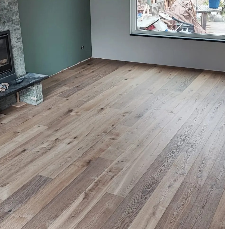 Brede eiken plankenvloer in een woonkamer met open haard